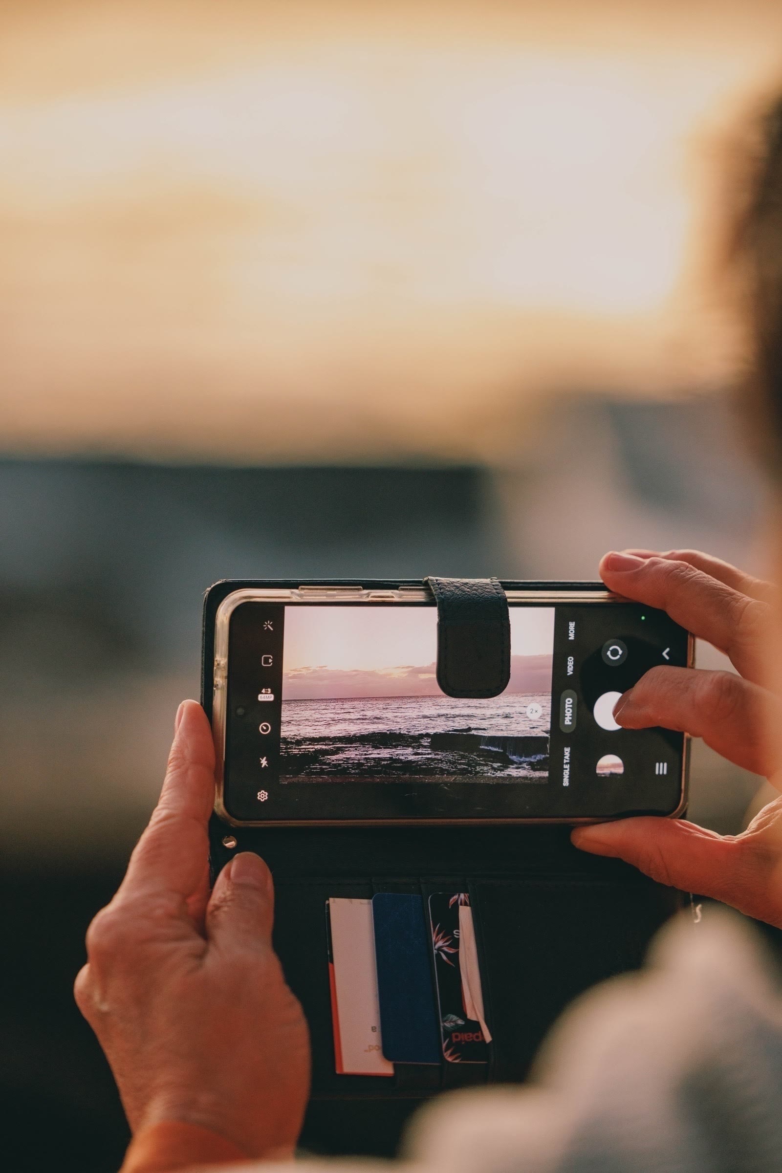 Person takign a photo of the sunrose on their iPhone at Snapper Rocks